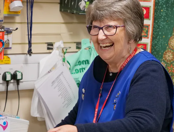 A volunteer smiling in the Friends shop